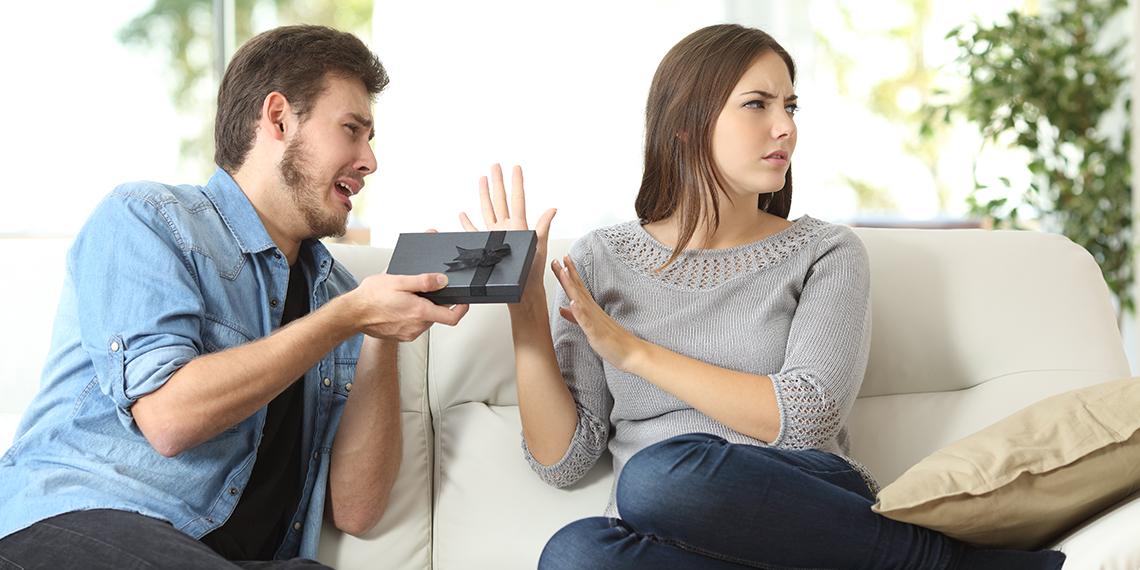 a man giving a gift to a woman who is unhappy