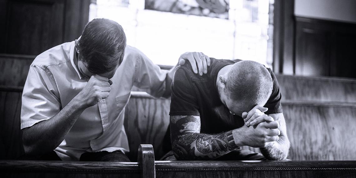two men praying together in church