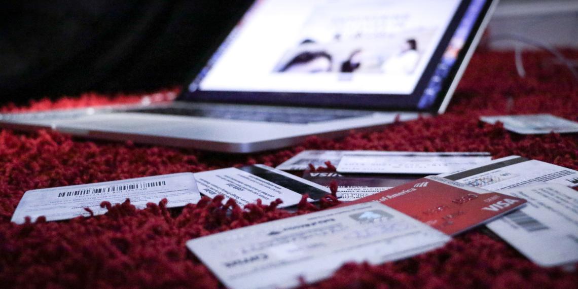 Scattered credit cards with a laptop in the background
