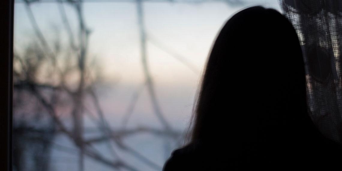 Silhouette of someone looking out a window at dusk