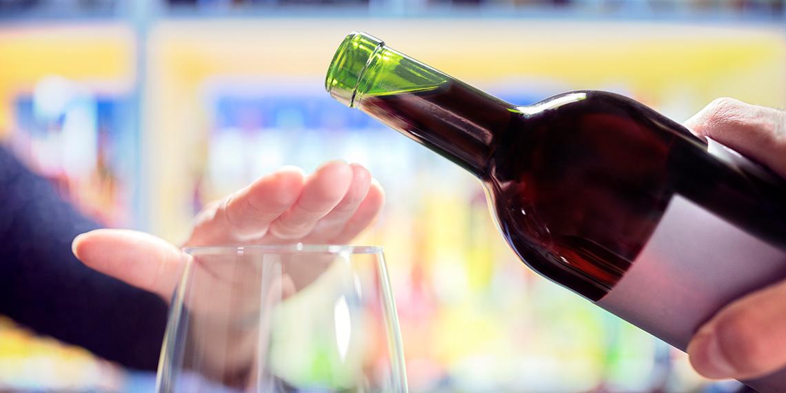 Womans hand rejecting more alcohol from wine bottle