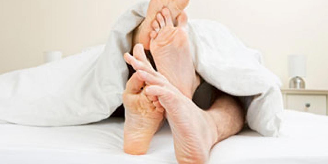 Two sets of feet poking out from under the covers