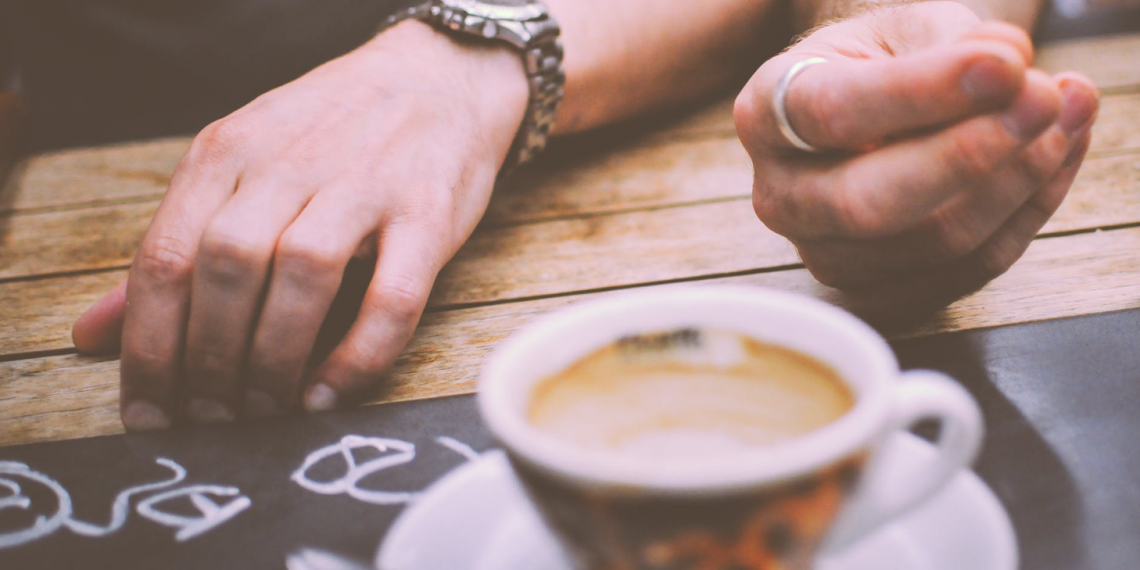 two hands by a cup of coffee